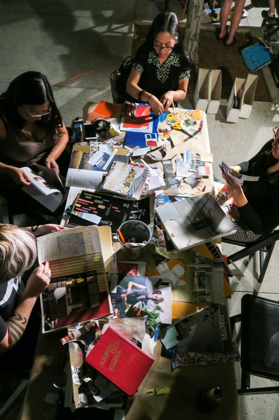 An overhead view of a worktable mid-session, paper scraps and supplies spread across it.
